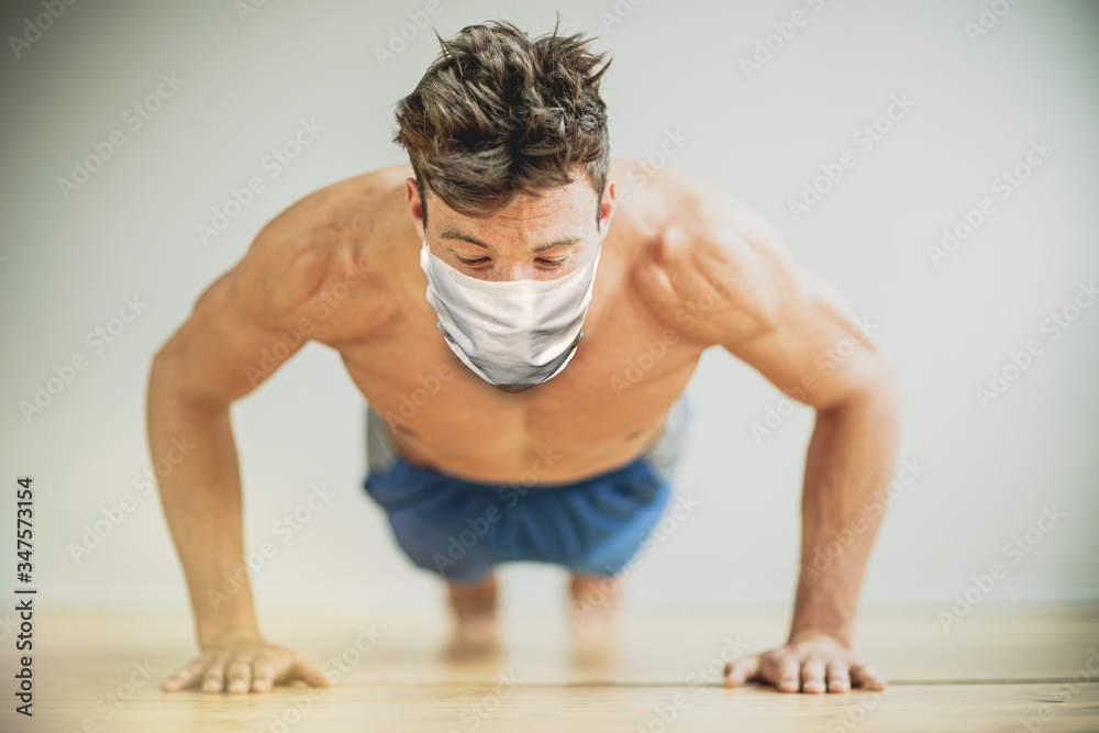 young man doing push ups in fitness studio with flu mask young man doing push ups in fitness studio with flu mask
