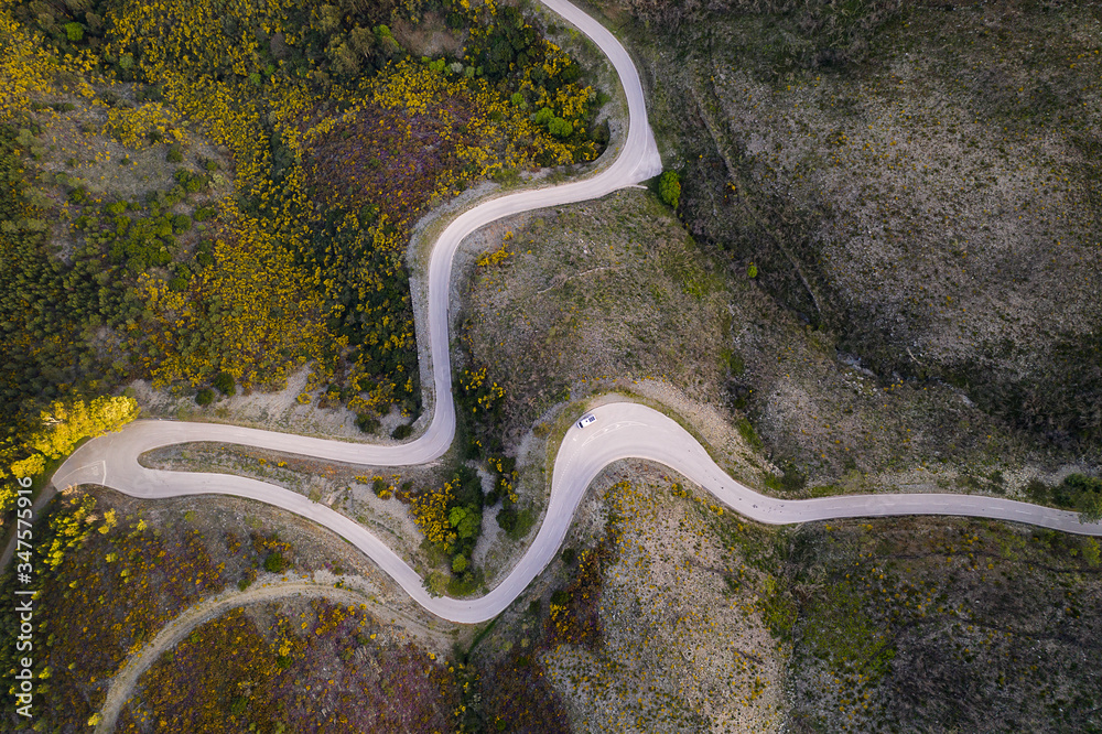 Beautiful drone aerial top view of road with curves in mountain landscape with a van social distancing near Piodao, Serra da Estrela in Portugal