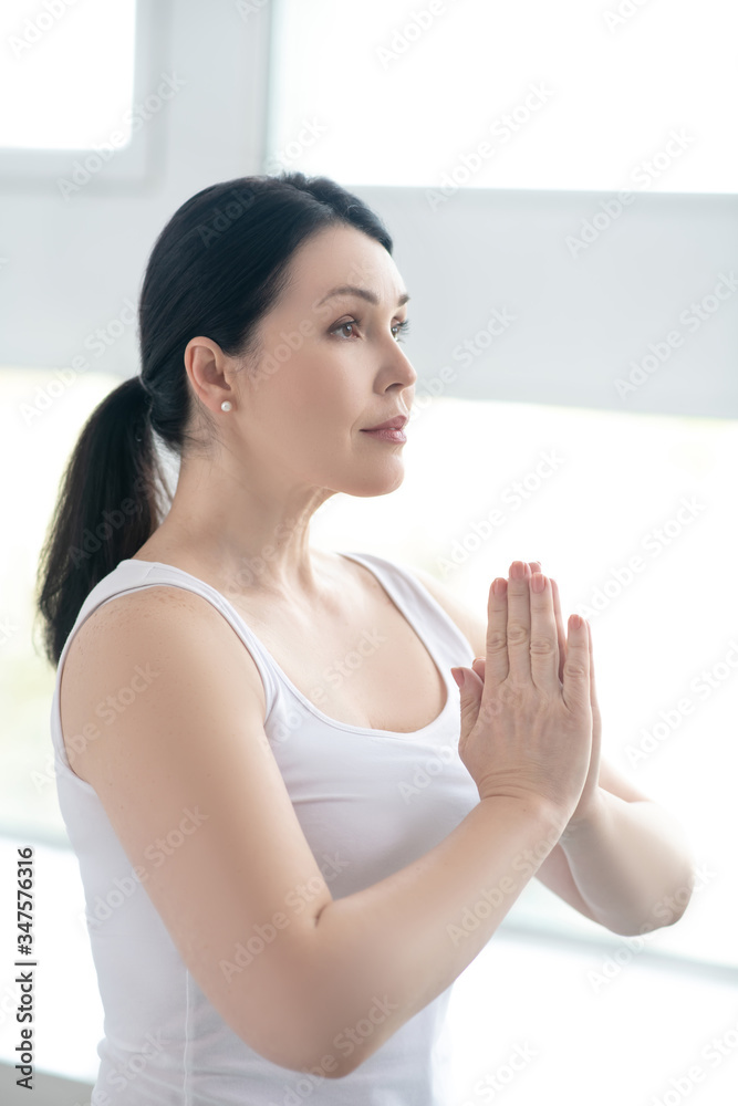 Brunette female performing namaste, pressing hands together Brunette female performing namaste, pressing hands together