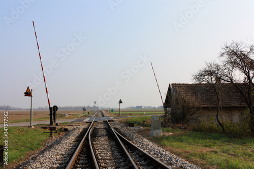 Railway to horizon perspective with opened barriers. Autumn. Blue sky.