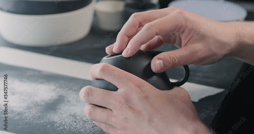 man hands polishing bottom of black ceramic cup