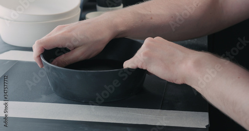 man hands sand bottom of black ceramic bowl