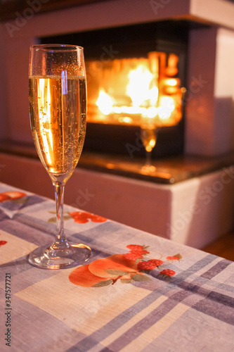 New Year or Christmas glass of champagne in front of the fireplace. Winter. Home.