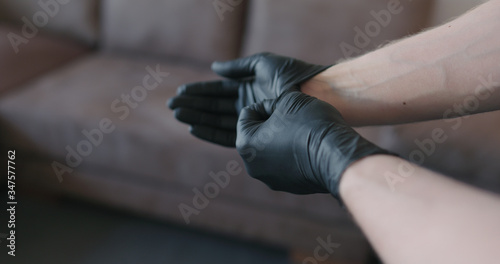Fototapeta Naklejka Na Ścianę i Meble -  man hands takes off black nitrile protective gloves indoors
