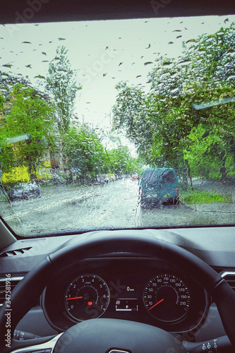 Photo of the windshield, steering wheel and driver's seat. Rain in autumn. Morning photo.