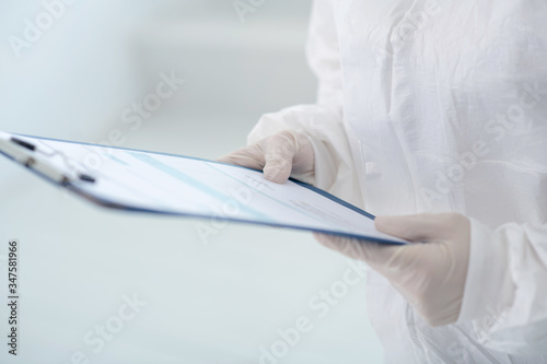 Close-up of medical worker hands in gloves holding clip folder