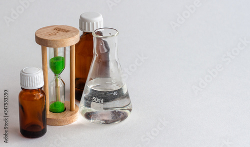Hourglass, the medical bulb and the medicine bottles on a white background. Place for the label. photo