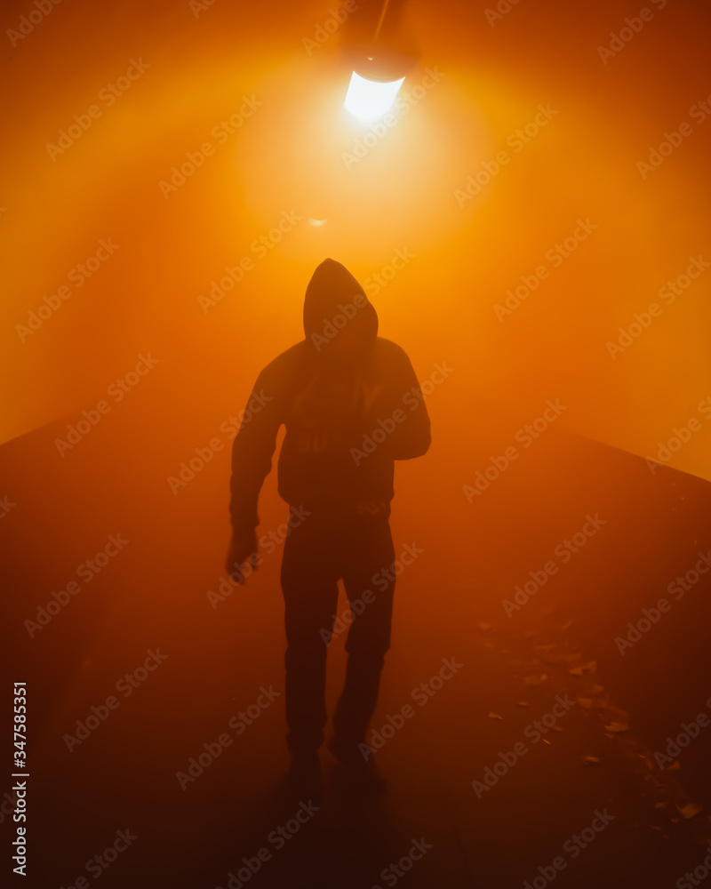 Silhouette of a man walking through a tunnel with coloured smoke