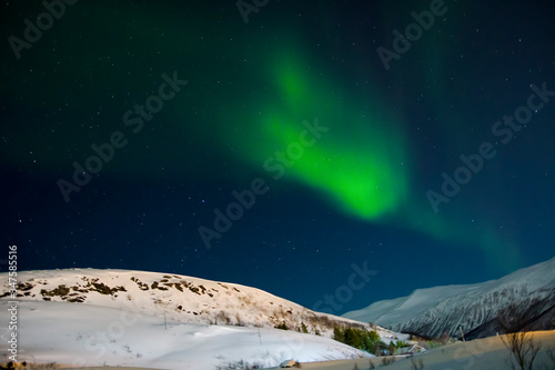 Zorza polarna nad zaśnieżonym wzgórzem. Zorza w Norwegii photo