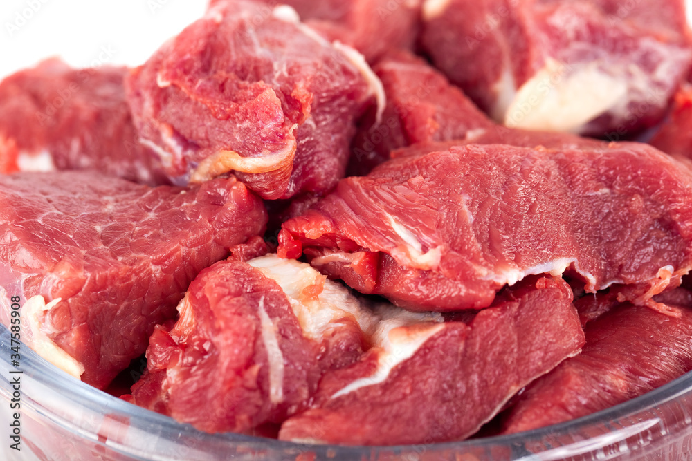 Pieces of fresh beef in a glass bowl isolated on white background