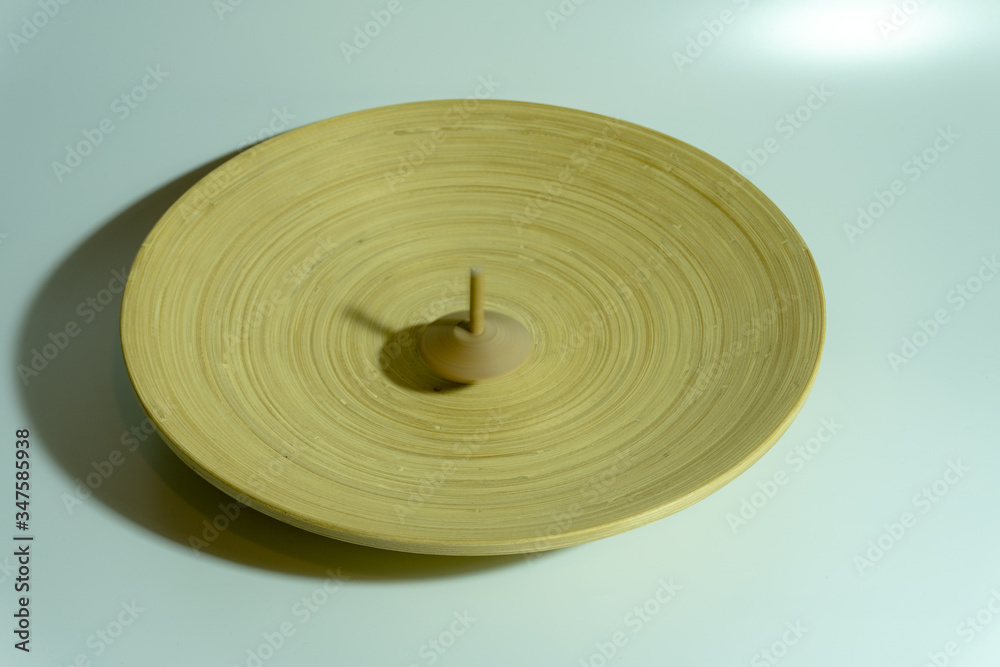 A Spinning Wooden Top on Wooden Round Plate - with Hand A Spinning Wooden Top on Wooden Round Plate - with Hand