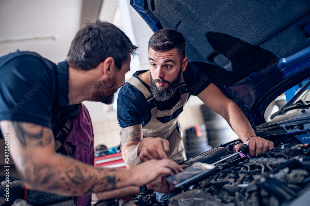 Young mechanics working in auto service Young mechanics working in auto service