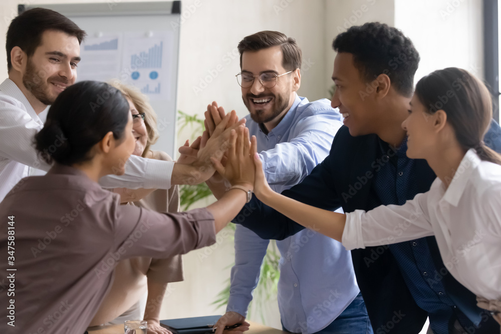 Diverse workers coach giving high five at company meeting. Happy multiracial colleagues with indian and black managers celebrating achievement, corporate success of teamwork, team building activity. Diverse workers coach giving high five at company meeting. Happy multiracial colleagues with indian and black managers celebrating achievement, corporate success of teamwork, team building activity.
