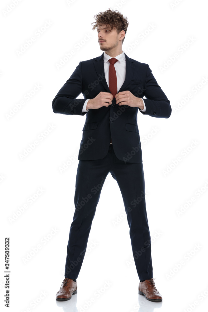 Determined businessman looking away and adjusting his jacket Determined businessman looking away and adjusting his jacket