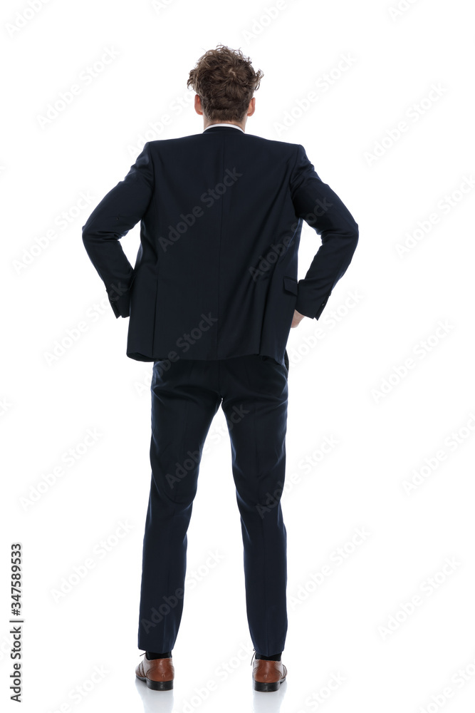 Rear view businessman holding both hands on his waist Rear view businessman holding both hands on his waist