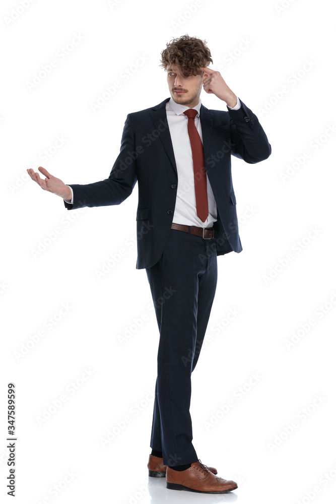 Side view of young businessman pointing to head