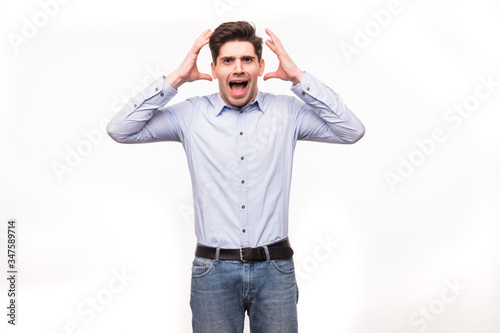 Young man screaming mouth open, hold head hand, wear casual blue shirt, isolated white background.