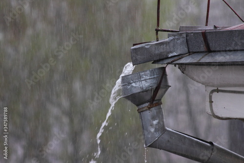 Slika na platnu A stream of rainwater from the roof overflows through the funnel of the old wate