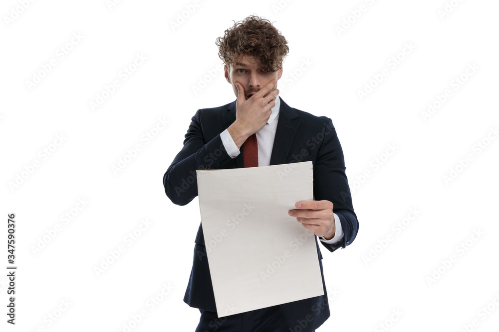 Surprised businessman reading newspaper gasping, covering his mouth Surprised businessman reading newspaper gasping, covering his mouth