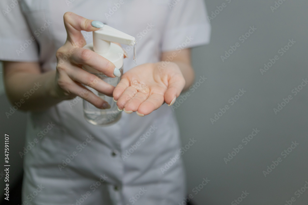 The girl is holding a liquid in a bottle. A doctor in a medical gown applies a disinfectant to his hands against bacteria and viruses. A nurse in white applies an antibacterial agent to her hands.