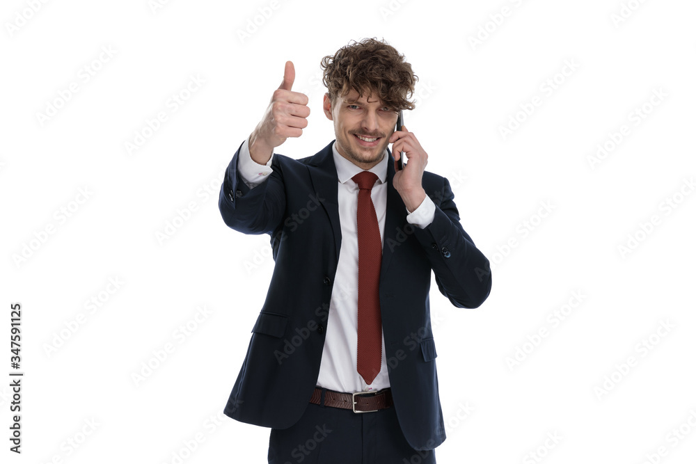 Positive businessman talking on phone and giving thumbs up