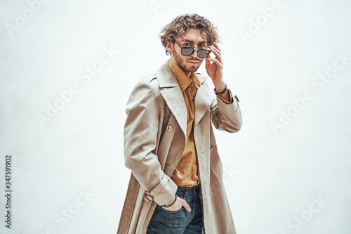 Self-assured and attractive male model standing in a bright studio wearing elegant clothes