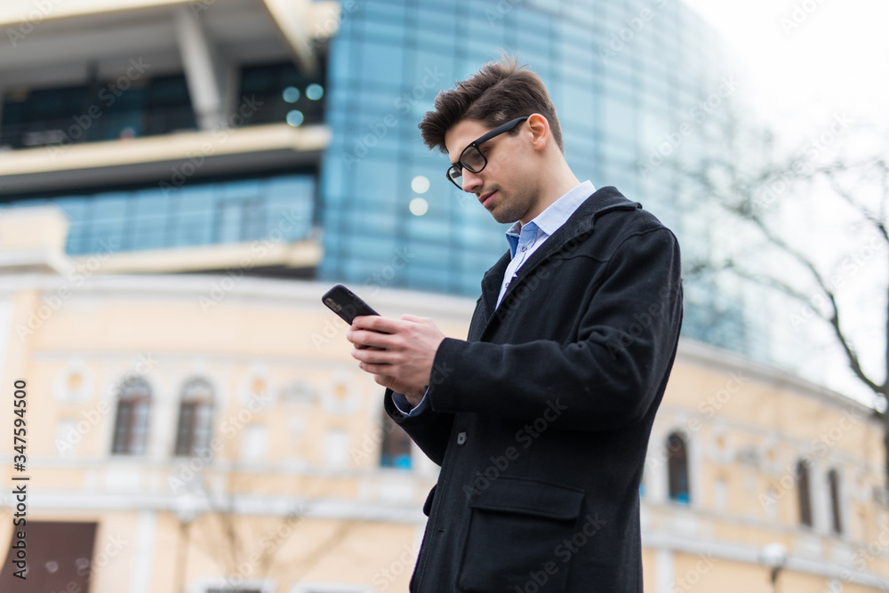 Handsome modern man using smart phone in the city