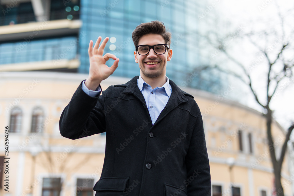 Young business man with okay gesture on the street