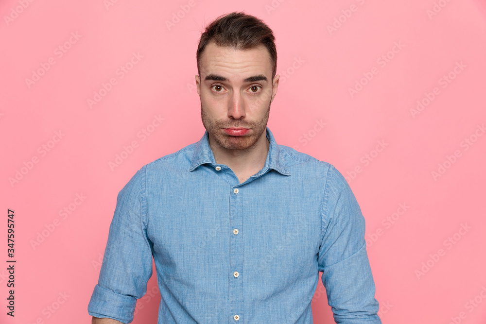 casual man is upset, standing and wearing a blue shirt casual man is upset, standing and wearing a blue shirt