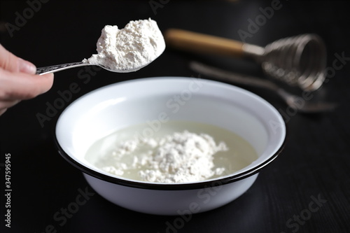 pour a spoonful of flour into a bowl to make dough for baking pizza and buns, cook at home according to family recipes