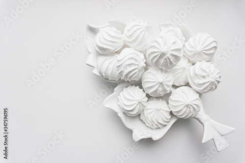 French vanilla meringue cookies baking for a bakery, coffee shop or sweet shop on white background. Homemade zephyr or marshmallow. Flat lay. Trendy top view dessert image. Invitation on coffee or tea