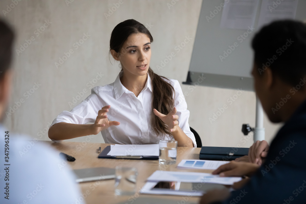 Attractive coach leader businesswoman talking and conducts negotiation in boardroom at meeting. Confidence woman training diverse corporate team at briefing. Young employee share thoughts sit at table Attractive coach leader businesswoman talking and conducts negotiation in boardroom at meeting. Confidence woman training diverse corporate team at briefing. Young employee share thoughts sit at table