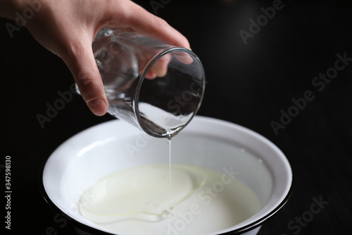 pour vegetable olive oil from a glass container of a glass into a bowl of water to make pizza dough and pies, cook at home in the kitchen for the family with love