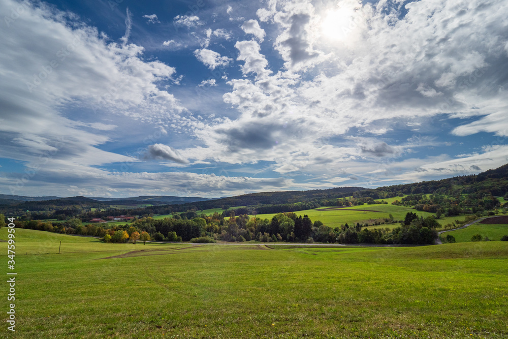Weitläufige Landschaft in der Rhön - Wiesen und Wald mit blauen Himmel und Wolken