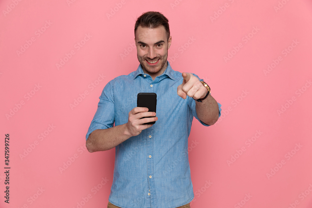 casual man pointing forward, writing a message on his phone casual man pointing forward, writing a message on his phone