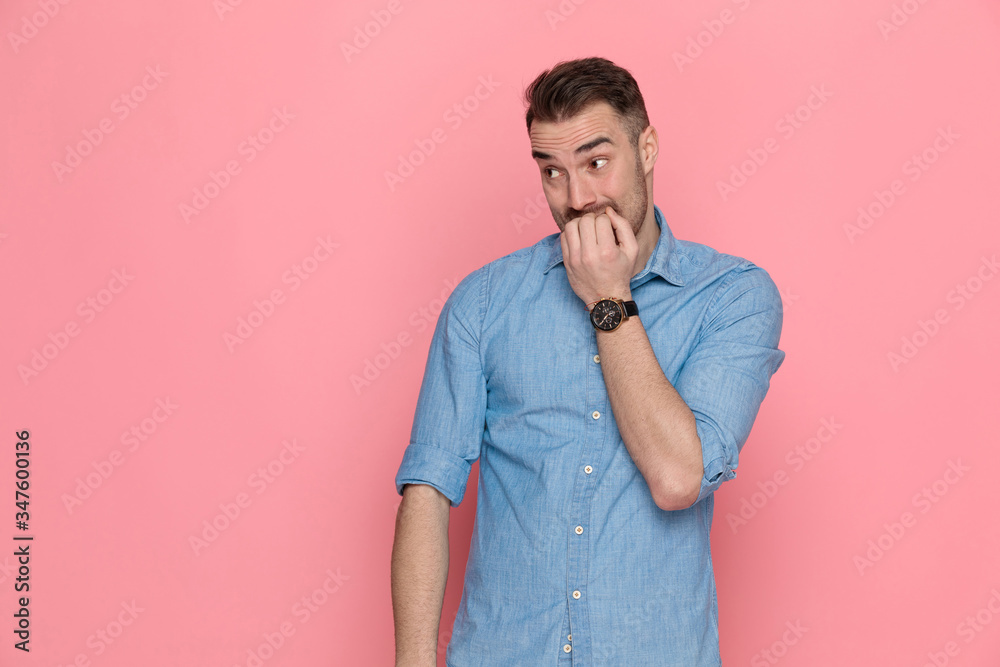 casual man looking aside, biting his nails