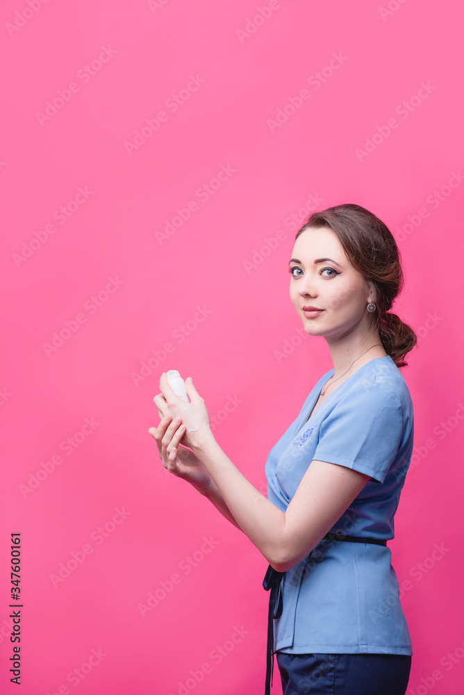 Girl puts cream on her hands on a pink background. The concept of skin care. Girl puts cream on her hands on a pink background. The concept of skin care.