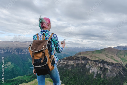 A beautiful girl stands high in the beautiful mountains with a compass in her hands. The concept of navigating the search for your own path and orientation to the cardinal points