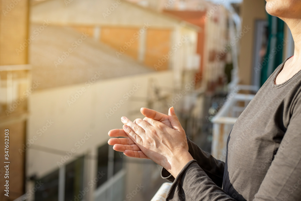 Fototapeta premium Woman applauding in a balcony of Spain greeting for works of doctors, nurses, policies during the coronavirus epidemic