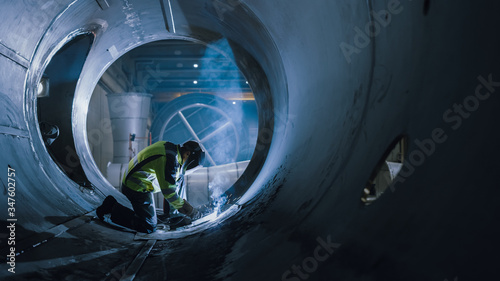 Professional Heavy Industry Welder Working Inside Pipe, Wears Helmet and Starts Welding. Construction of the Oil, Natural Gas and Fuels Transport Pipeline. Industrial Manufacturing Factory