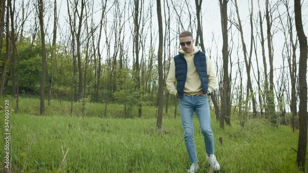 Man walks in the forest park. Walks on young fresh green grass. Man walks in the forest park. Walks on young fresh green grass.