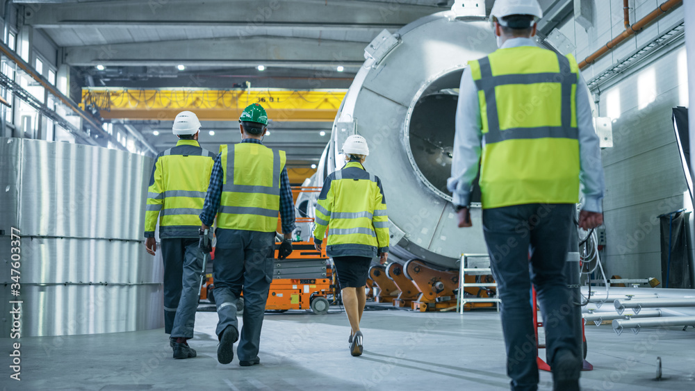 Shot of Heavy Industry Engineers and Workers Walking through Pipe Manufacturing Factory. Modern Facility for Design and Construction of Oil, Gas and Fuels Transport Pipeline. Low Angle Shot of Heavy Industry Engineers and Workers Walking through Pipe Manufacturing Factory. Modern Facility for Design and Construction of Oil, Gas and Fuels Transport Pipeline. Low Angle