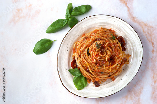 Pasta with tomato sauce, sun-dried tomatoes and olives on a light background