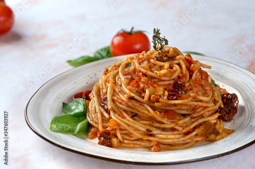 Pasta with tomato sauce, sun-dried tomatoes and olives on a light background