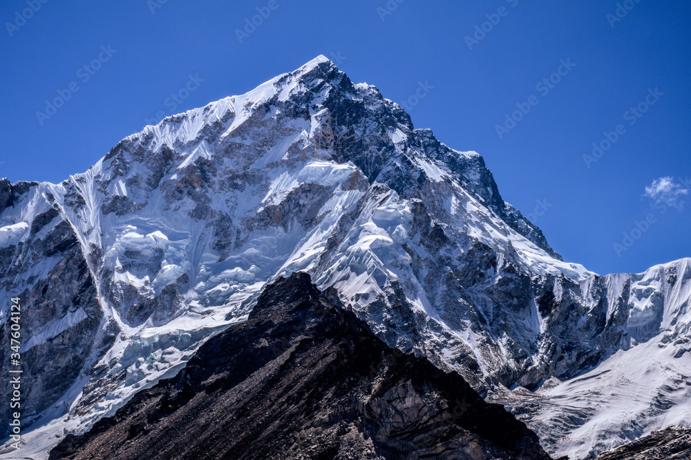 Snow mountain peak of nepal himalayas in background with dark mountains in foreground 