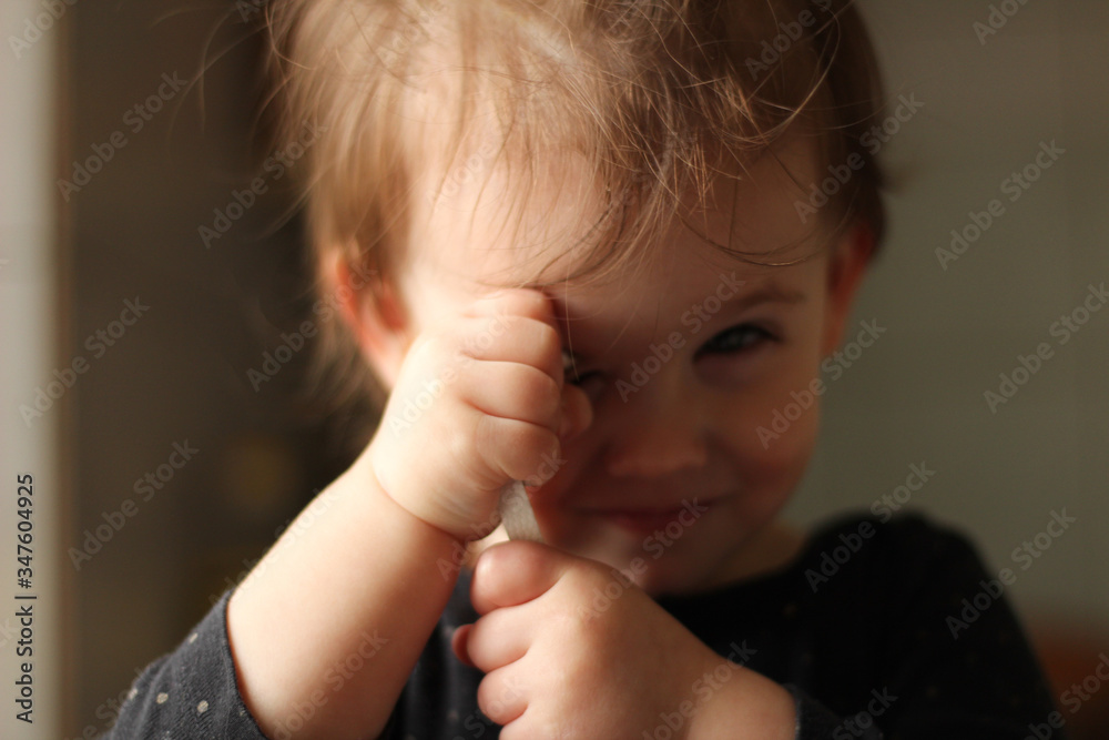 Close-up portrait of a little cute white baby with a dirty face in soft light and blurry background