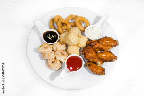 Chicken wings appetizer, squid rings, breaded shrimp and rice balls in pastry, as well as soy, tomato and mayonnaise sauces