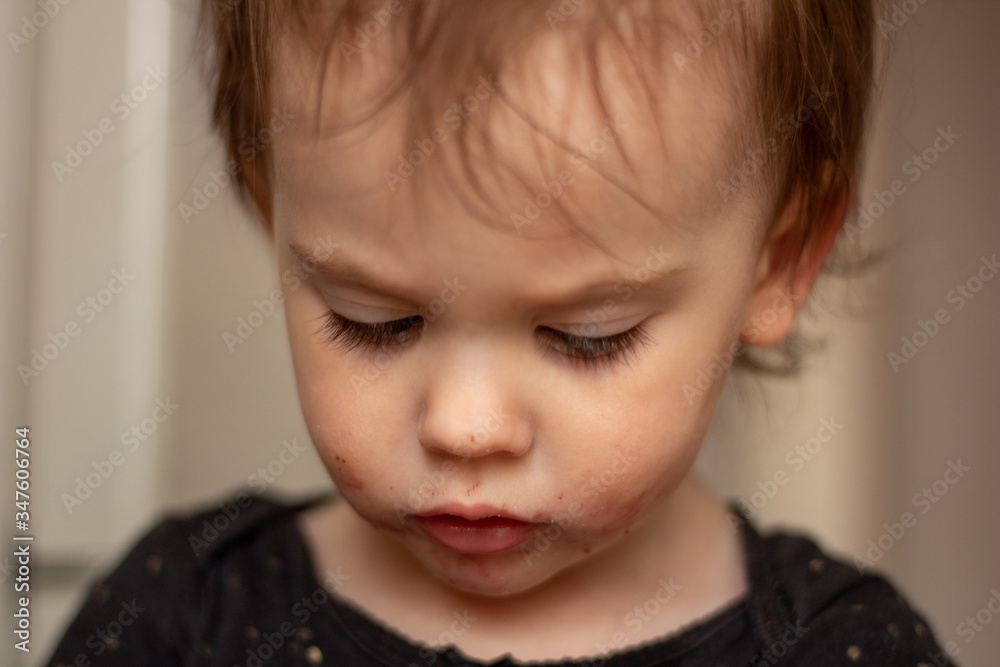 Close-up portrait of a little cute white baby with a dirty face in soft light and blurry background Close-up portrait of a little cute white baby with a dirty face in soft light and blurry background