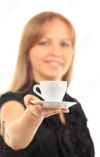 Beautiful young woman with big smile serving an espresso. Cup is sharp, model out of focus. Isolated on white.