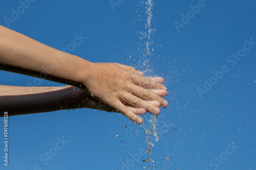 Jugendliche Hände unter Wasserstrahl reiben und waschen